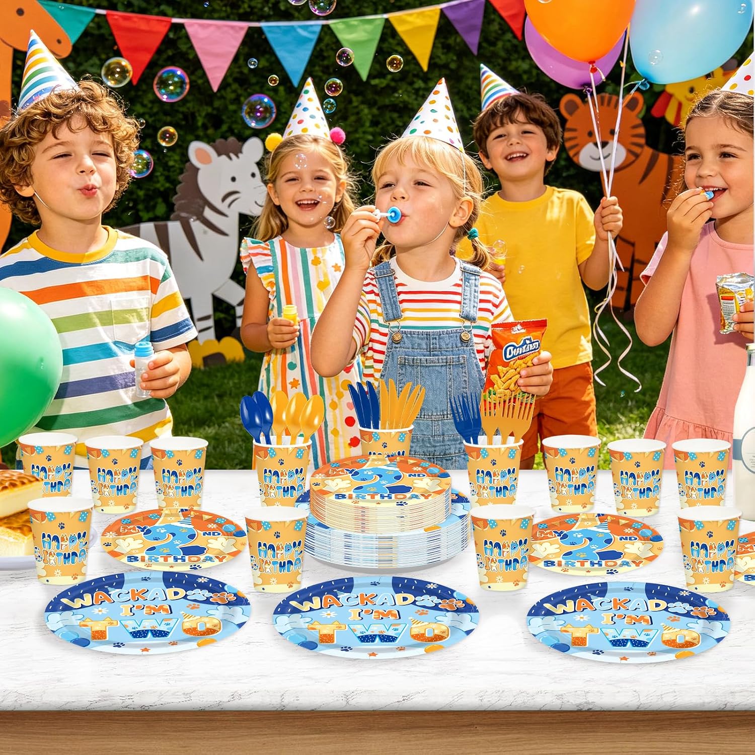 Kids celebrating a 2nd birthday with Grencian blue dog tableware set, balloons, bubbles, party hats and snacks on a bright outdoor table