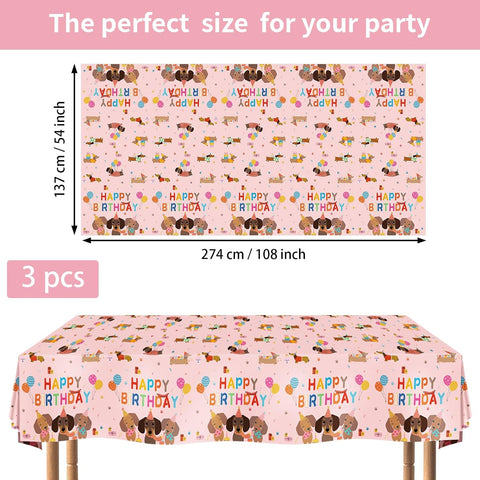 Flat lay of three dachshund birthday tablecloths with pink background and cartoon dog pattern